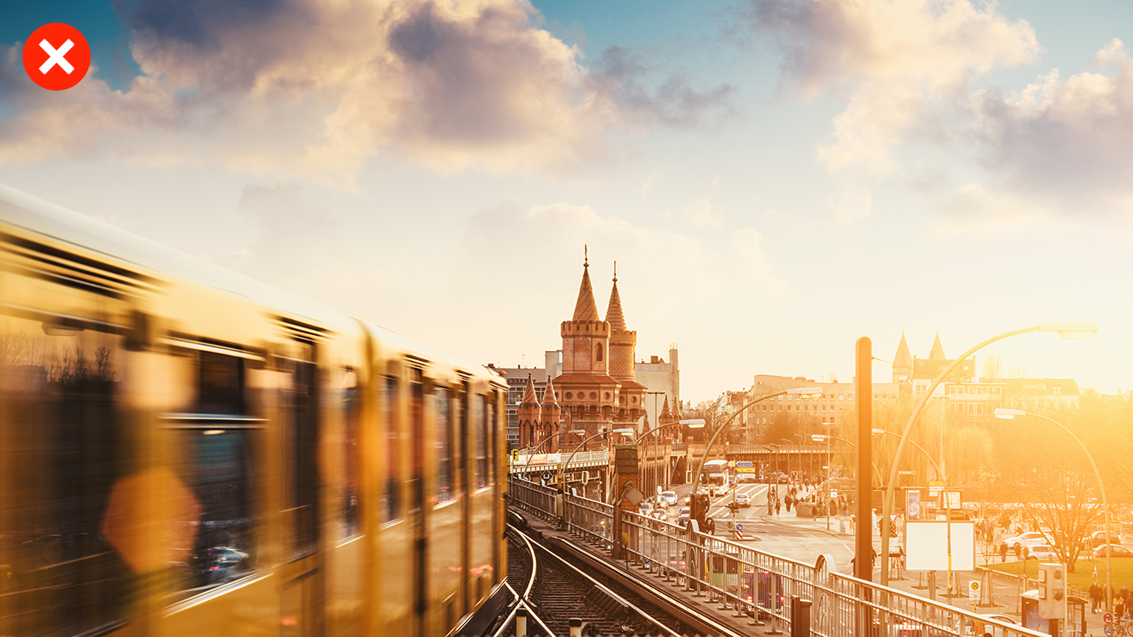 Eine U-Bahn fährt bei Sonnenuntergang über eine Brücke in einer urbanen Umgebung. Das Bild ist teilweise überbelichtet und unscharf.