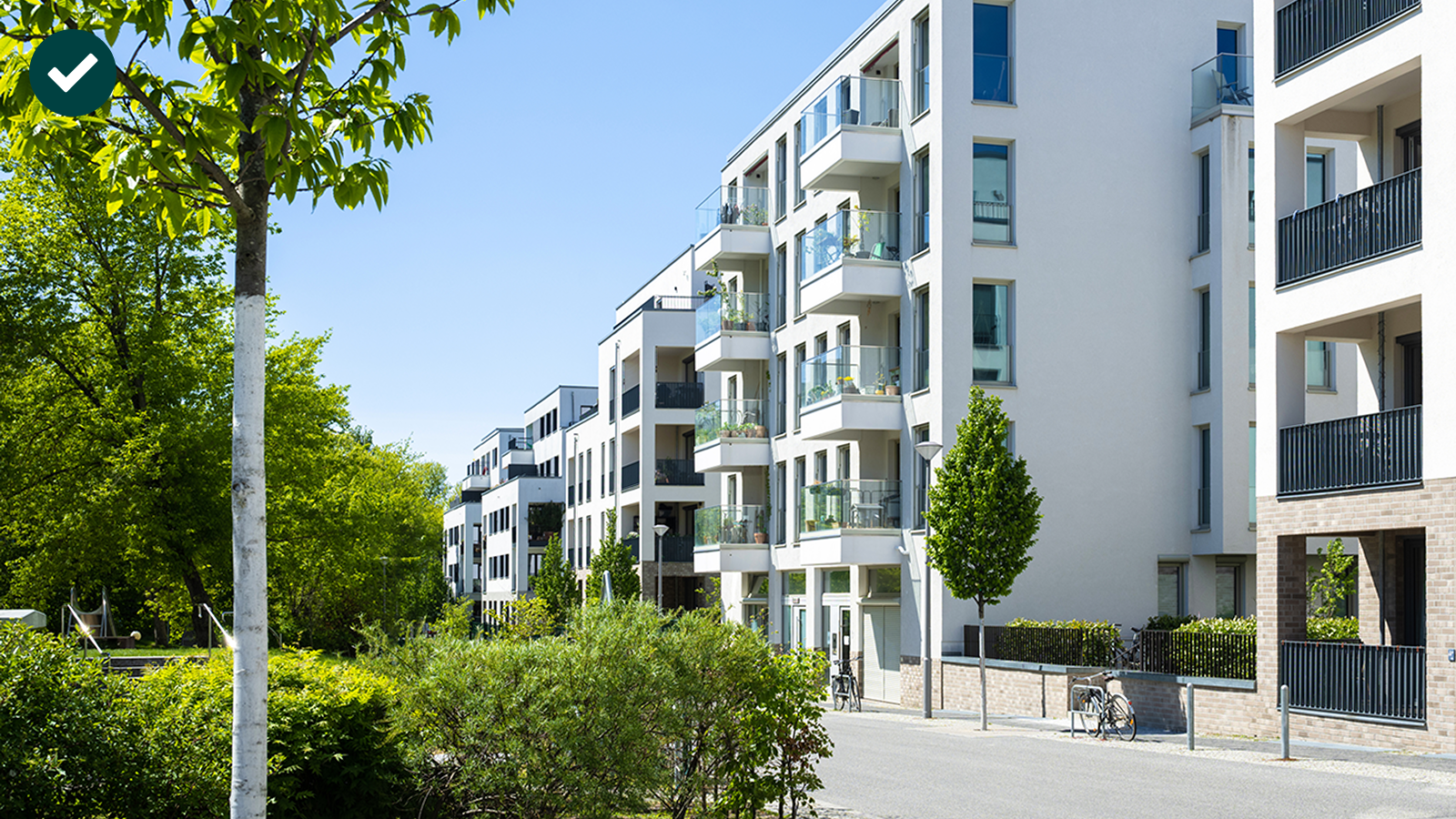 Moderne Wohngebäude mit Balkonen und grüner Umgebung unter klarem blauen Himmel.